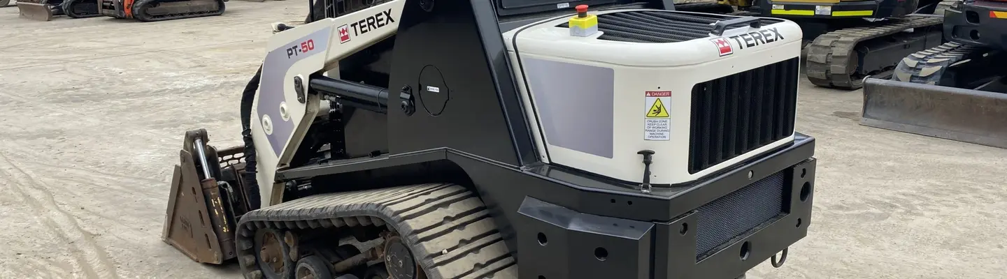 A truck loader attachment positioned on a construction site, ready for installation or use with heavy machinery.