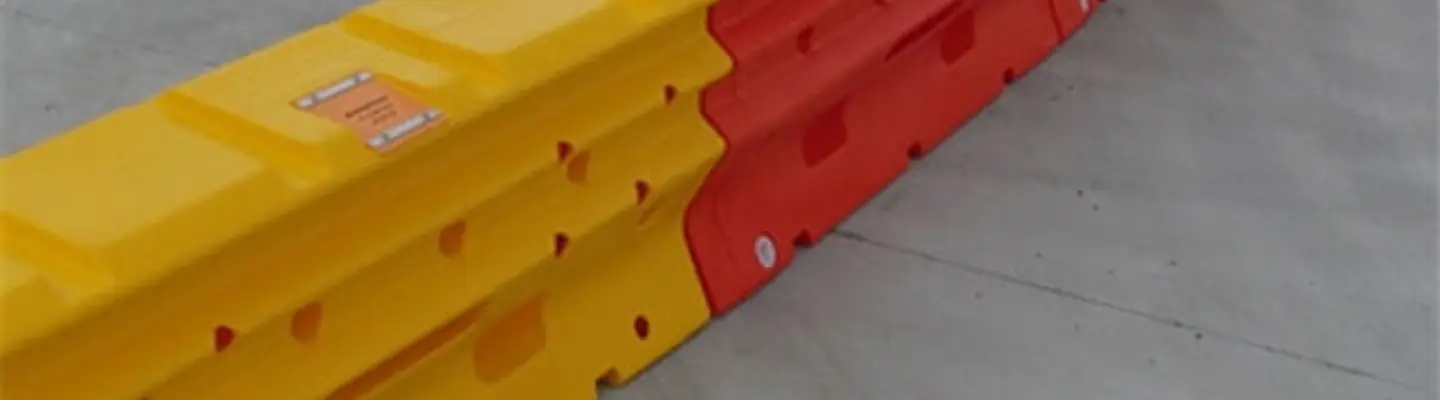 Water-filled safety barriers lined up along a road construction site to manage traffic and protect workers.