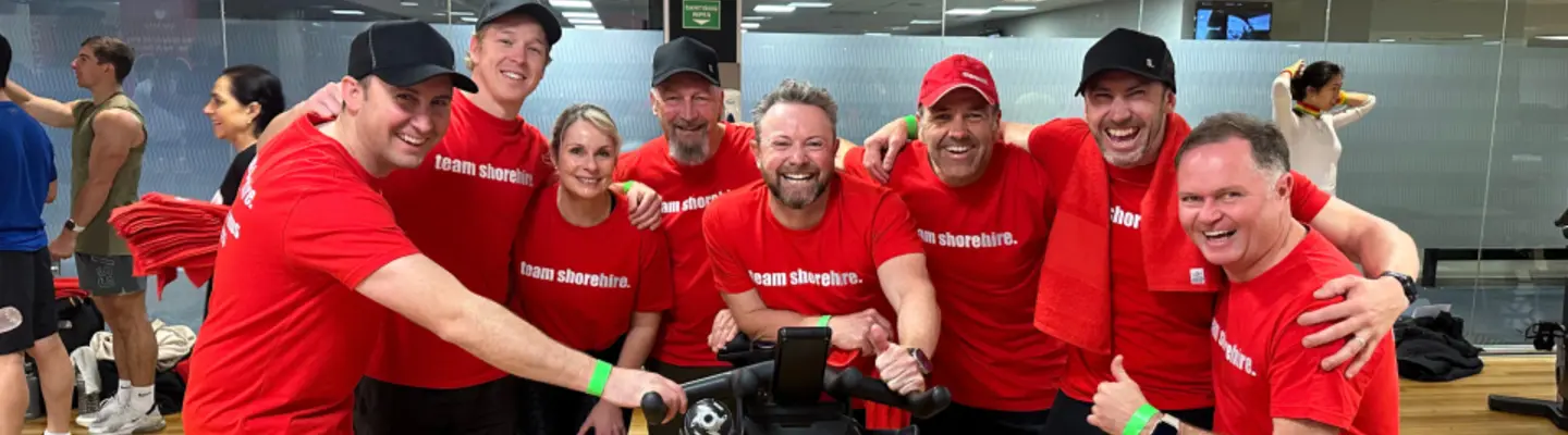 Group of smiling personnel exercising together in a gym, promoting team wellness and positive workplace culture.