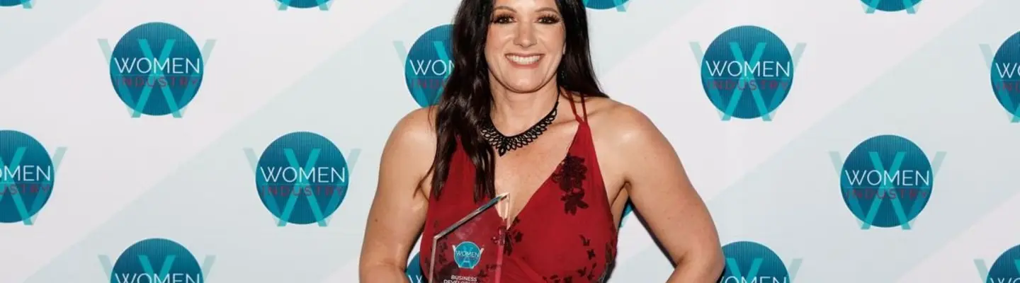 Smiling employee holding an award in front of a company-branded backdrop, recognized for excellence in site safety and barrier services.