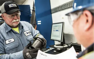 two workers discussing an equipment part at a counter
