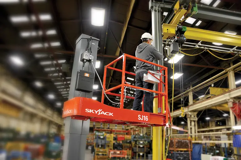 Worker on an orange Skyjack electric one-person lift