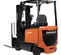 Rear angled view of an orange and black Doosan warehouse forklift with a black mast and forks and an open cabin.