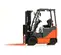 Side view of an orange and black Toyota warehouse forklift with a black mast, orange forks and an open cabin.