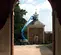 Wide side view of an extended blue Genie boom lift with a worker on the platform in an indoor warehouse.