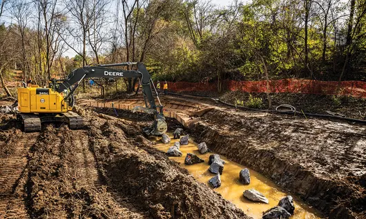 Yellow John Deere excavator digging in the dirt