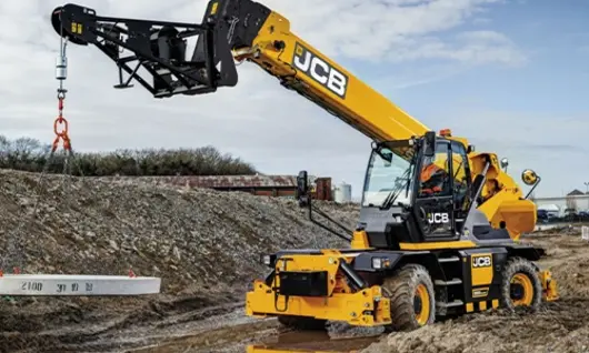 Worker operating machinery at a construction site during safety barrier installation to improve roadside protection.