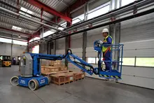 Worker on electric boom lift inside a warehouse