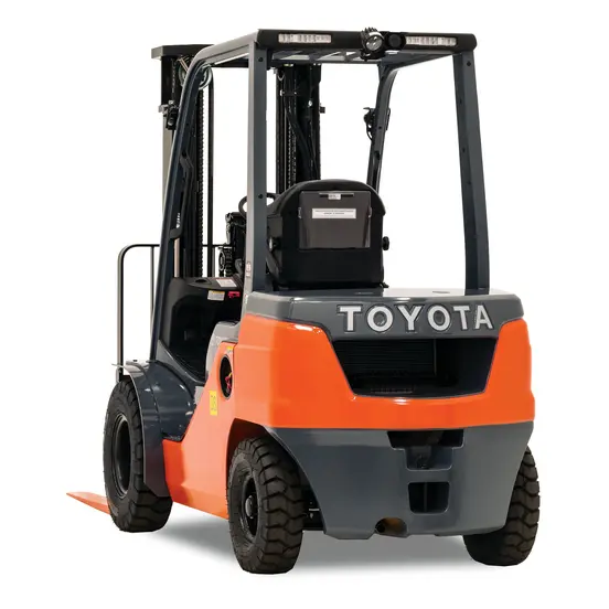 Rear view of orange and black Toyota warehouse forklift with black lifting mast and orange forks with an open cabin.
